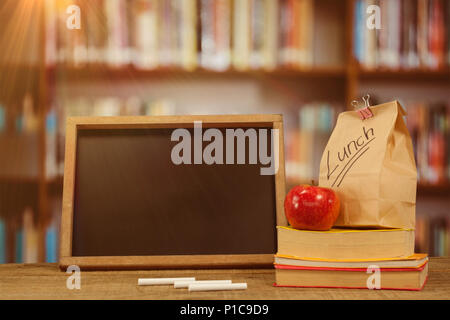 Composite image of slate with chalks by lunch bag and books on wooden table Stock Photo