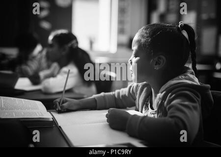 Attentive schoolgirl doing her homework in classroom Stock Photo