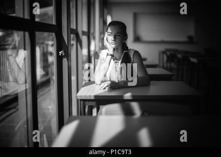 Thoughtful schoolgirl sitting in classroom Stock Photo