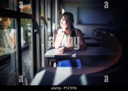 Thoughtful schoolgirl sitting in classroom Stock Photo