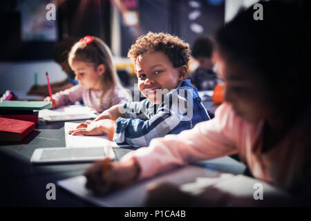 Portrait of smiling schoolboy doing his homework in classroom Stock Photo