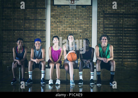High school kids sitting on a bench in basketball court Stock Photo
