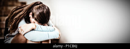 Sad schoolgirl sitting alone on staircase Stock Photo