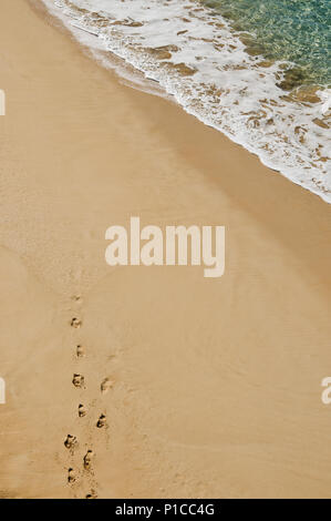 Looking down at footprints disappearing on on the yellow sand of Makena beach (Big beach) Maui, Hawaii. Stock Photo