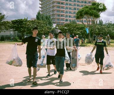 Japan Air Self-Defense Force members carry away trash collected during a beach cleanup Oct. 9, 2016, at Sunset Beach in Okinawa, Japan. Volunteers from Kadena and Naha Air Bases came together to build partnership and relations during the event. (U.S. Air Force photo by Senior Airman Omari Bernard) Stock Photo