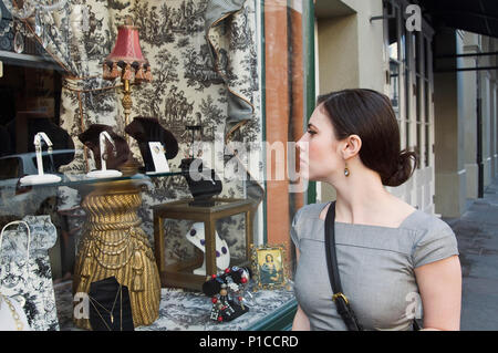 A young woman window shopping for antiques on Royal street in New Orleans Stock Photo