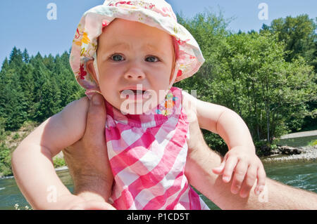 A father holding a crying 11 month old baby outdoors. Stock Photo