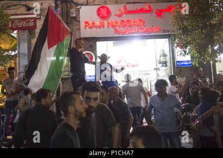 Ramallah, Palestinian Territories, West Bank. 10th June, 2018. A man waves a Palestinian flag during an anti-Mahmoud Abass protest.Palestinians gathered in Al-Manara Square to march in protest of Mahmoud Abass and the Palestinian Authority. A group of pro-Abass supporters briefly scuffled with protesters, however the march remained peaceful after. Credit: Matthew Hatcher/SOPA Images/ZUMA Wire/Alamy Live News