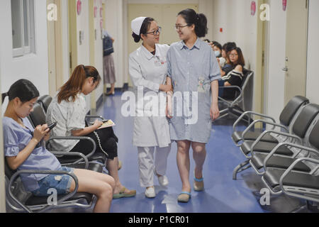 (180612) -- FUZHOU, June 12, 2018 (Xinhua) -- A nurse guides a pregnant woman who made the reservation for regular check on cell phone at Fujian Provincial Maternity and Children's Hospital in Fuzhou, capital of southeast China's Fujian Province, June 12, 2018. Fujian Provincial Maternity and Children's Hospital has improved the facilities and its services in recent years. New building was constructed and high technology is used. Patients are able to file documents, receive instructions ahead of delivery and reserve massaging for newborns through cell phones. (Xinhua/Song Weiwei)(wsw) Stock Photo