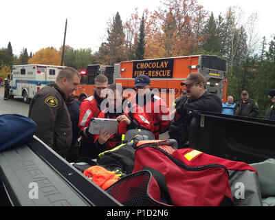 Petty Officers Gerard Gagnon, Tim Koscielny and Terry Bailey coordinate operations with local search teams Oct. 18 ,2016, near the Chocolay River in Marquette, Michigan. Crews worked with the Chocolay Fire Department evacuating citizens from their homes located along the river. (U.S. Coast Guard photo by Station Marquette) Stock Photo