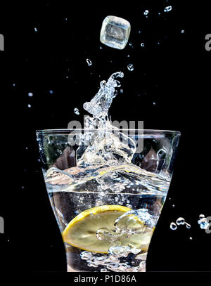 Ice Cubes dropping into  glass of water creating a splash Stock Photo