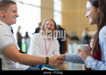 Businesswomen shaking hands at conference Stock Photo