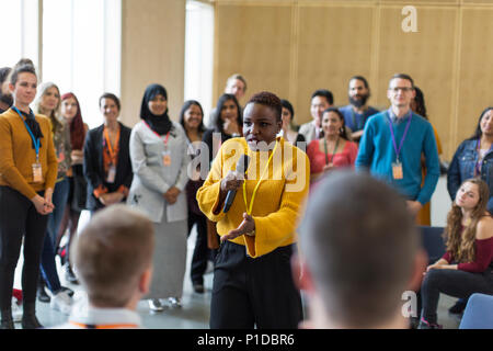 Conference audience listening to businesswoman speaker with microphone Stock Photo