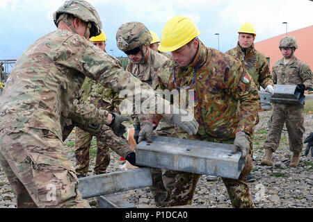 Italian army soldiers from the 2nd Engineer Regiment Pointieri Piacenza and U.S. Army paratroopers assigned to the 173rd Airborne Brigade, 54th Brigade Engineer Battalion, work together to assemble component items of a bridge during exercise Livorno Shock at Leghorn Army Depot in Italy, Oct. 21, 2016. Livorno Shock is a combined readiness exercise led by the Italian army's 2nd Engineer Regiment Pontieri and is designed to familiarize U.S. Army paratroopers with river crossing tactics, techniques and procedures. The 173rd Airborne Brigade is the U.S. Army's Contingency Response Force in Europe, Stock Photo