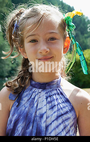 A young girl wearing ribbons in her hair, smiling at the camera. Stock Photo