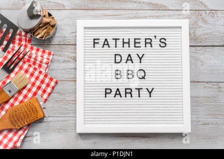 Father's Day BBQ Party sign on a white memo board with cooking tools. Stock Photo