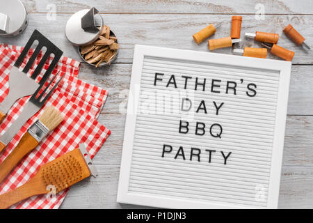 Father's Day BBQ Party sign on a white memo board with cooking tools. Stock Photo