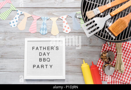 Father's Day BBQ Party sign on a white memo board with cooking tools. Stock Photo