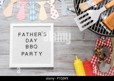 Father's Day BBQ Party sign on a white memo board with cooking tools. Stock Photo