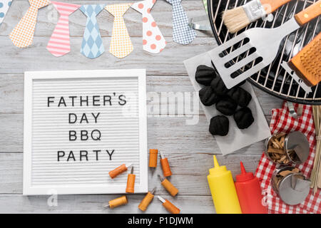 Father's Day BBQ Party sign on a white memo board with cooking tools. Stock Photo