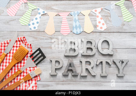 BBQ Party sign with BBQ cooking tools on a wood background. Stock Photo