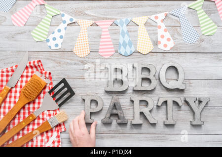 BBQ Party sign with BBQ cooking tools on a wood background. Stock Photo