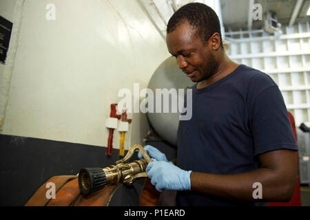 161014-N-IE397-041    ARABIAN GULF (Oct. 14, 2016) Petty Officer 3rd Class Kennedy Ogonda, from Nairobi, Kenya, shines a varinozzle in the hangar bay of the aircraft carrier USS Dwight D. Eisenhower (CVN 69) (Ike). Ogonda serves aboard Ike as an aviation boatswain's mate (handling) and helps direct aircraft in the hangar bay and on the flight deck. Ike and its Carrier Strike Group are deployed in support of Operation Inherent Resolve, maritime security operations and theater security cooperation efforts in the U.S. 5th Fleet area of operations. (U.S. Navy photo by Seaman Christopher A. Michael Stock Photo