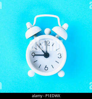 White alarm clock on a pastel blue, pink background Stock Photo