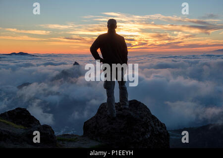 Man looks at Roque Bentayga above the clouds at sunset, Gran Canaria, Canary Islands, Spain Stock Photo