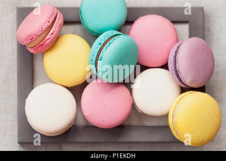 Fresh natural colorful macarons of different tastes in wooden frame, unusual abstract sweet art, gourmet picture Stock Photo