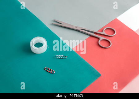 On colorful sheets of paper are scissors, paper clips, tape. Stock Photo