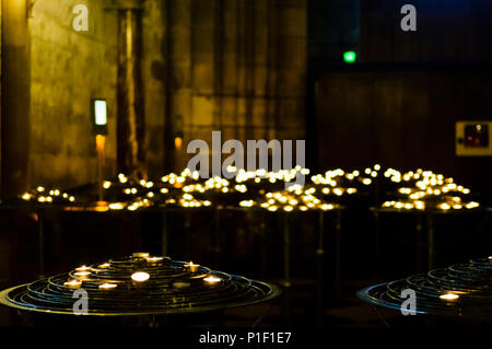 Lit candles in Notre Dame Cathedral in Paris.  Shallow depth of field, with bokeh on candles in the background.  Dark, moody, image with copy space. Stock Photo