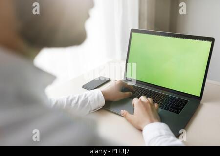 Young Man sitting at a table at home working on a laptop compute Stock Photo