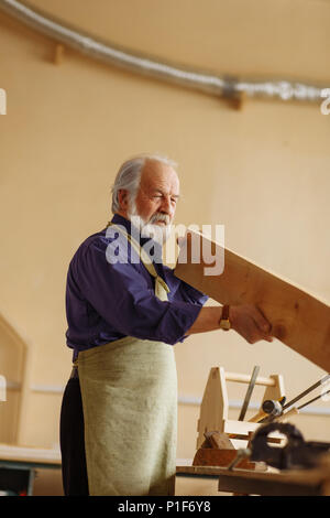 retiree with grey hair measuring the plaank with nacked eyes Stock Photo