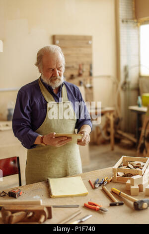 close up portrait of old carpenter using his tablet computer Stock Photo