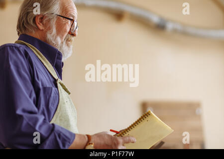 close-up side view cropped portrait of old carpenter with notepad Stock Photo