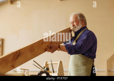 old craftsperson is working with timber indoors Stock Photo