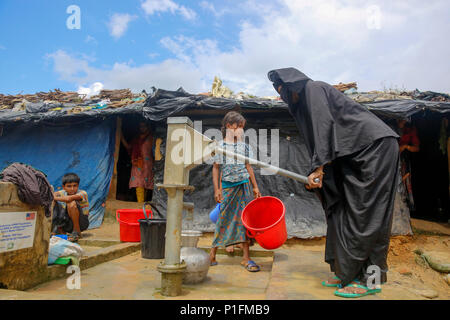 A Rohingya refugee woman collects drinking water at  Kutupalong refugee camp at Ukhiya in Cox's Bazar, Bangladesh Stock Photo