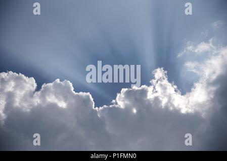 Sunrays: atmospheric coditions highlight the rays of the sun bursting from behind Cumulus cloud Stock Photo