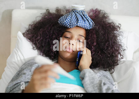 Woman With Fever Using Thermometer And Calling Doctor By Phone Stock Photo
