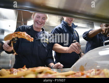 161022-N-BT947-063 PACIFIC OCEAN - (Oct. 22, 2016) Lt. j. g. Jennifer Abbott serves pizza with other junior officers aboard the amphibious transport dock ship USS Somerset (LPD 25). Somerset is on its maiden deployment as part of the Makin Island Amphibious Ready Group, with the embarked 11th Marine Expeditionary Unit in support of the Navy's maritime strategy in the U.S. 3rd, 5th, and 7th Fleet areas of responsibility. (U.S. Navy Photo by Petty Officer 2nd Class Jacob I. Allison) Stock Photo