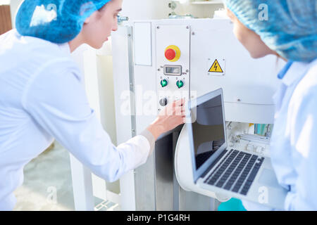 Two  Young Women Setting Machines at Food Factory Stock Photo