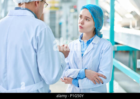 Young Woman Listening to Plant Supervisor Stock Photo