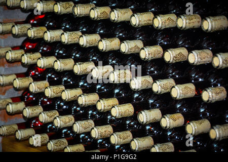 Bottles of domestic wine. Resting wine bottles stacked on iron racks in cellar. Stock Photo