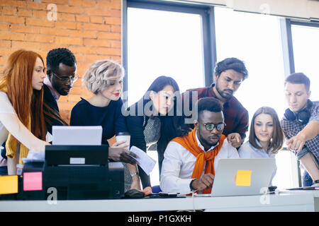 closeup shot of young mixed race people gathering round the table Stock Photo