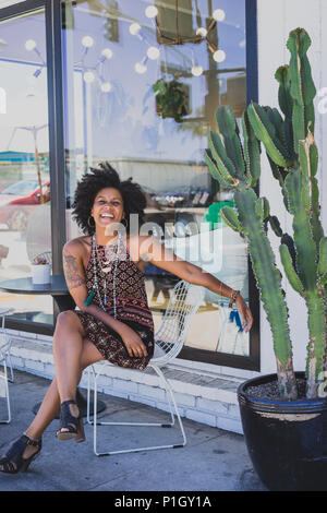 Laughing black woman sitting outside a coffee shop Stock Photo