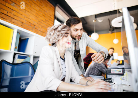 two young attractive employees are looking at the funny photos on the computer Stock Photo