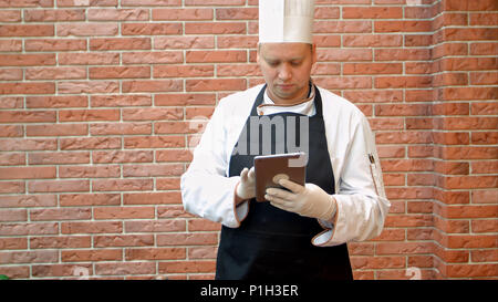 Chef using his digital tablet in the kitchen Stock Photo