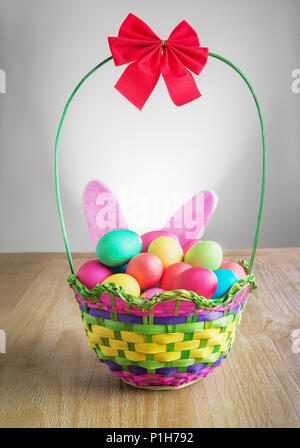 multicolored  Easter eggs in the wattled basket  on vintage wooden table Stock Photo