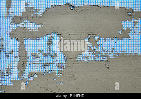 The texture of the wall, covered with gray foam polystyrene plates, covered with a blue reinforcing mesh and covered with a mixture for gluing it. Sta Stock Photo